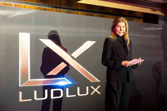 Fechamento da experiência no palco, com a marca LudLux projetada