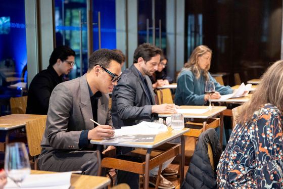 Participantes registrando decisões nas mesas de trabalho